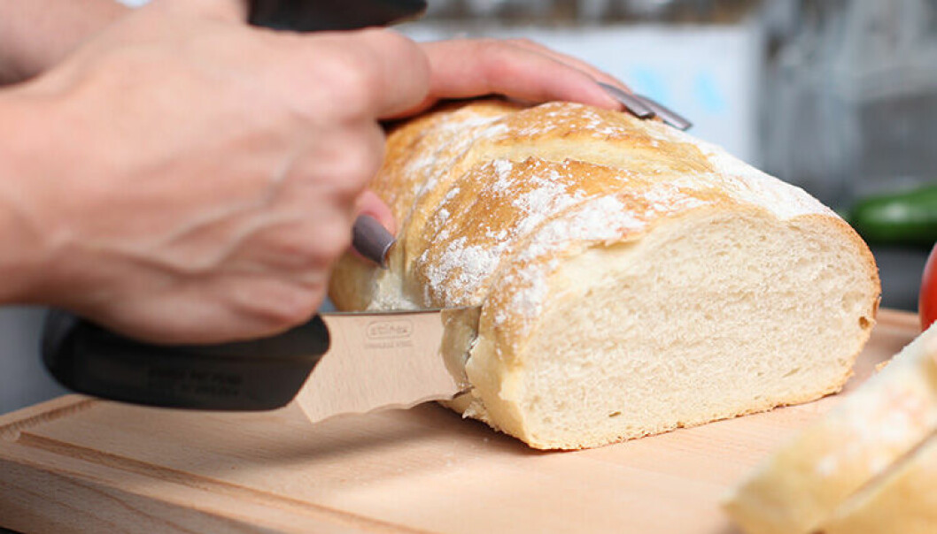 Ergonomisk brödkniv skär igenom en limpa vitt bröd.