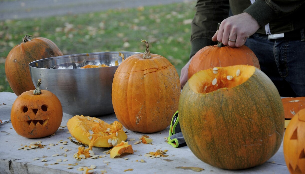 Ett bord där en person står och gör lyktor till halloween och allhelgonahelgen.