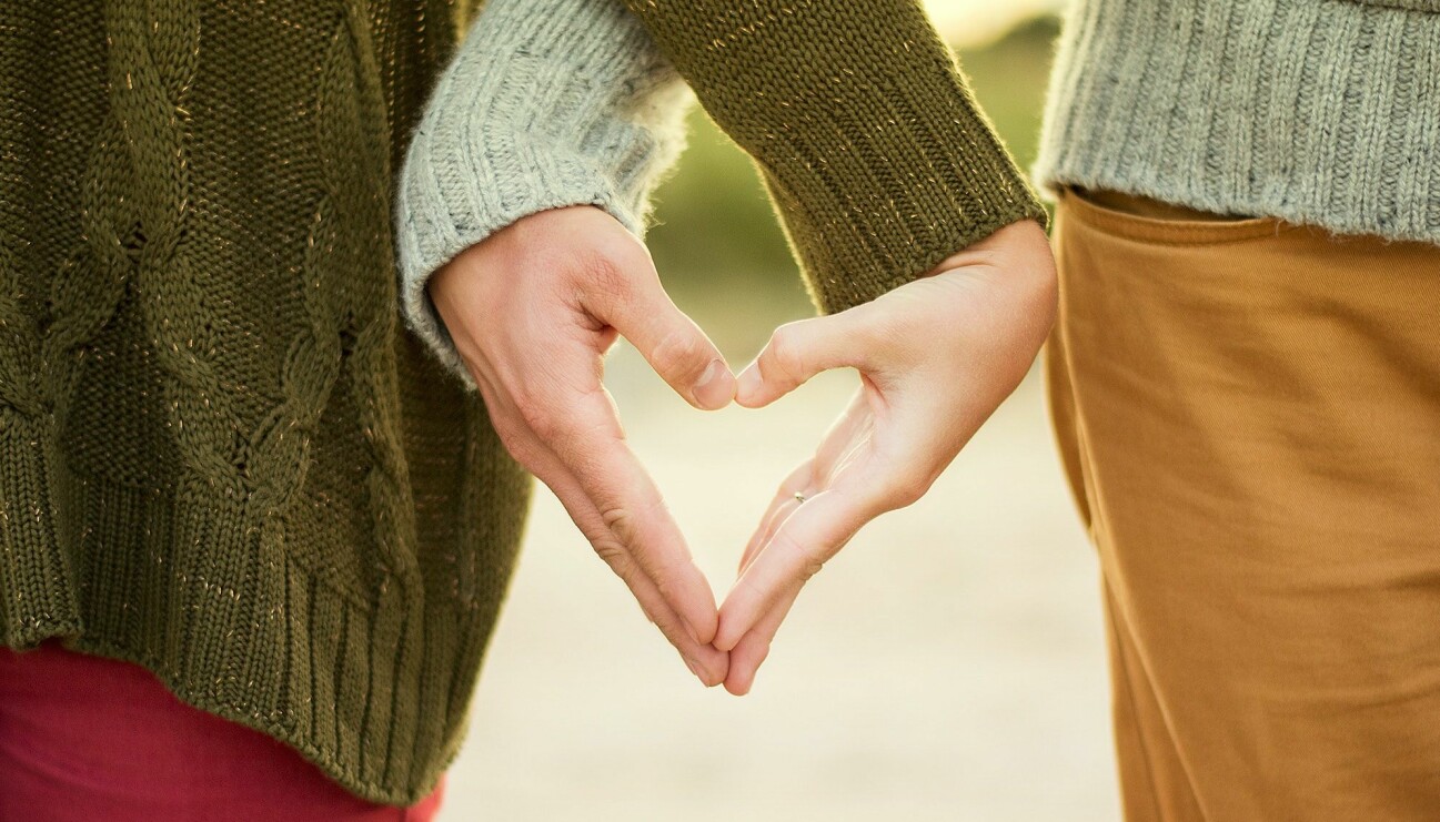 Ett par som gemensamt skapar ett hjärta med sina händer.