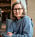 Psykolog Eva Lyberg sitter i en grå fåtölj och tittar in i kameran. hon är klädd i en gråblå ylletröja och har glasögon och axellångt ljust hår. I bakgrunden syns böcker i en hylla.
