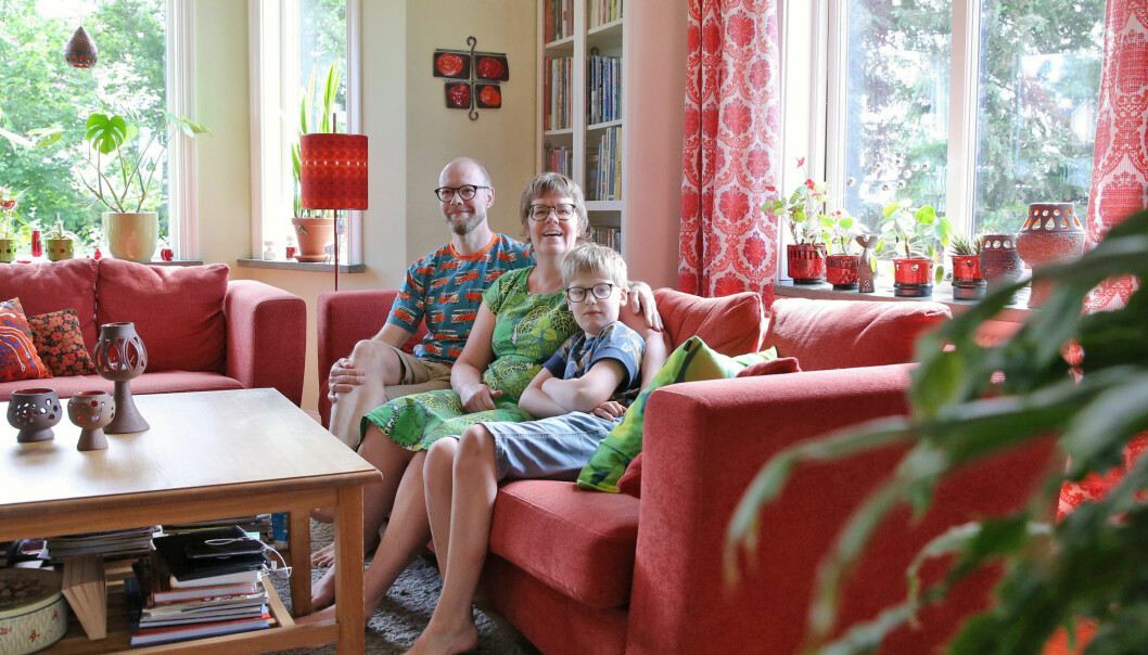 Familjen Holgersson sitter i sin röda soffa.