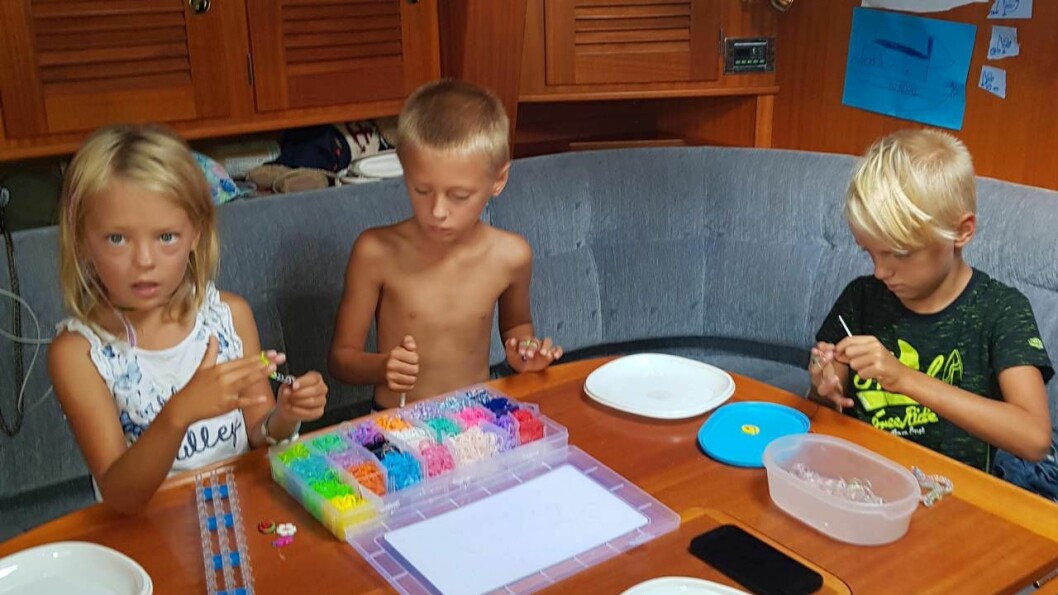 Skolarbete mitt på Atlanten. Wilma, Lucas och Maximilian har med sig en massa böcker och pyssel på resan. Foto: Privat Wilma, Lucas och Maximilian pysslar på båten
