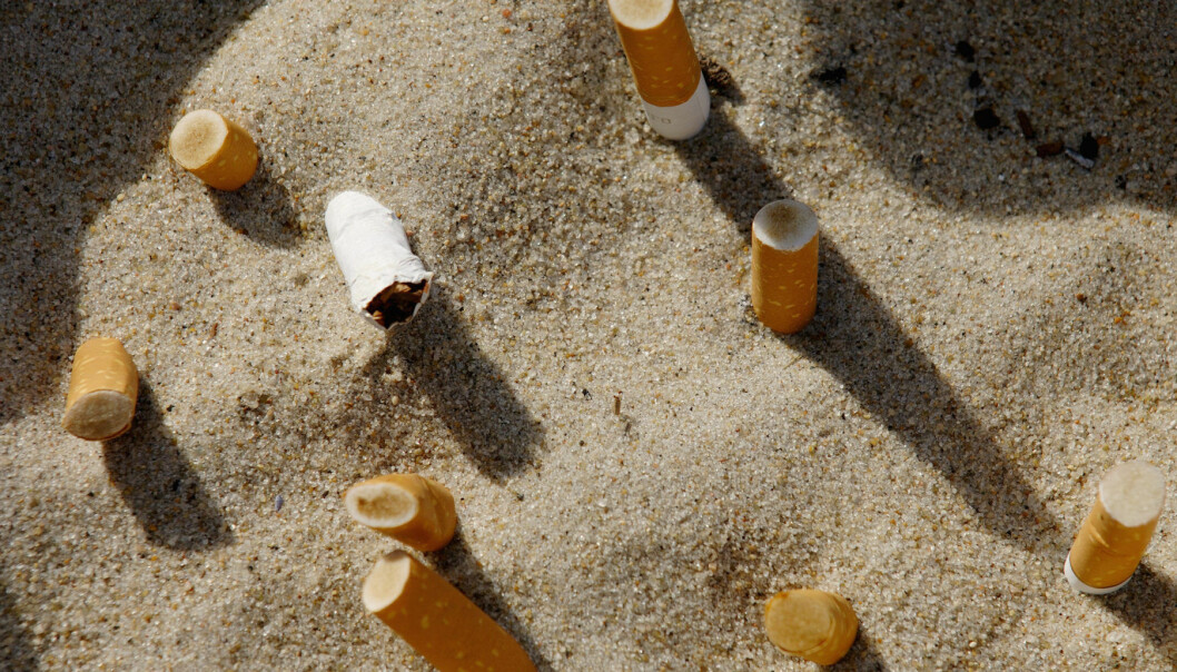 Cigarettfimpar nedtryckta i sand
