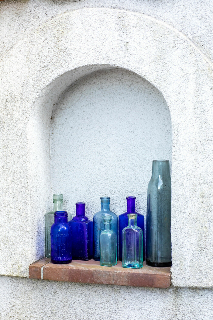 Flaskor i olika blå toner står i en smyg