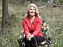Författaren Anna Kansell sitter i en blommig fåtölj som är placerad på en äng.