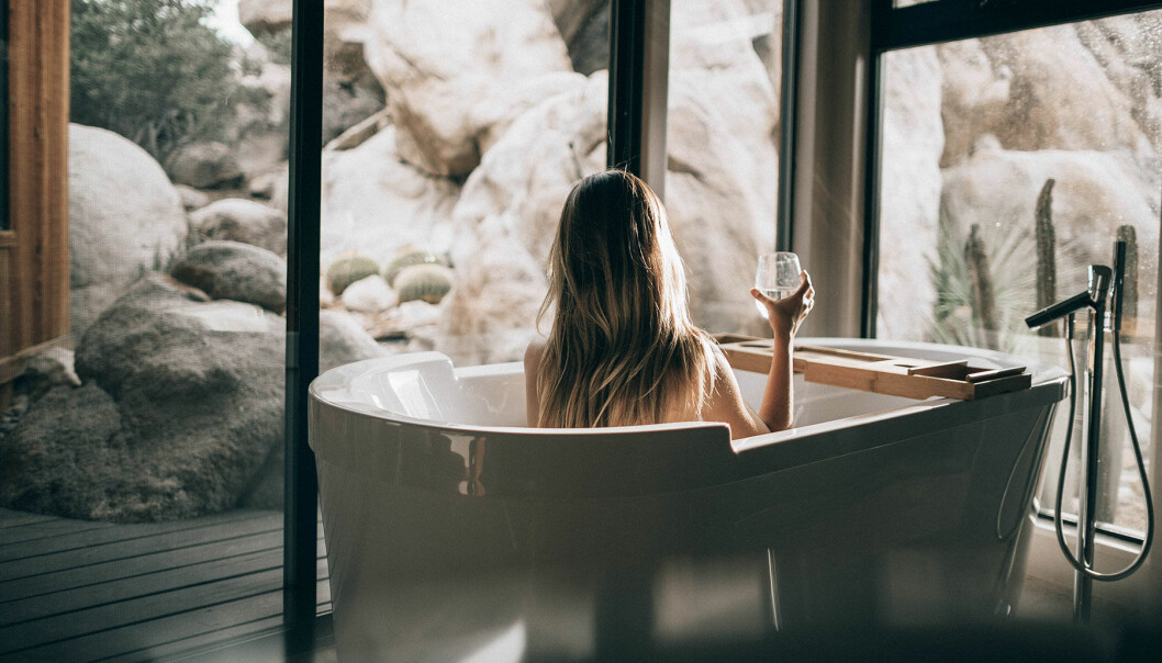 Kvinna i badkar med ett glas i ett lyxigt badrum.