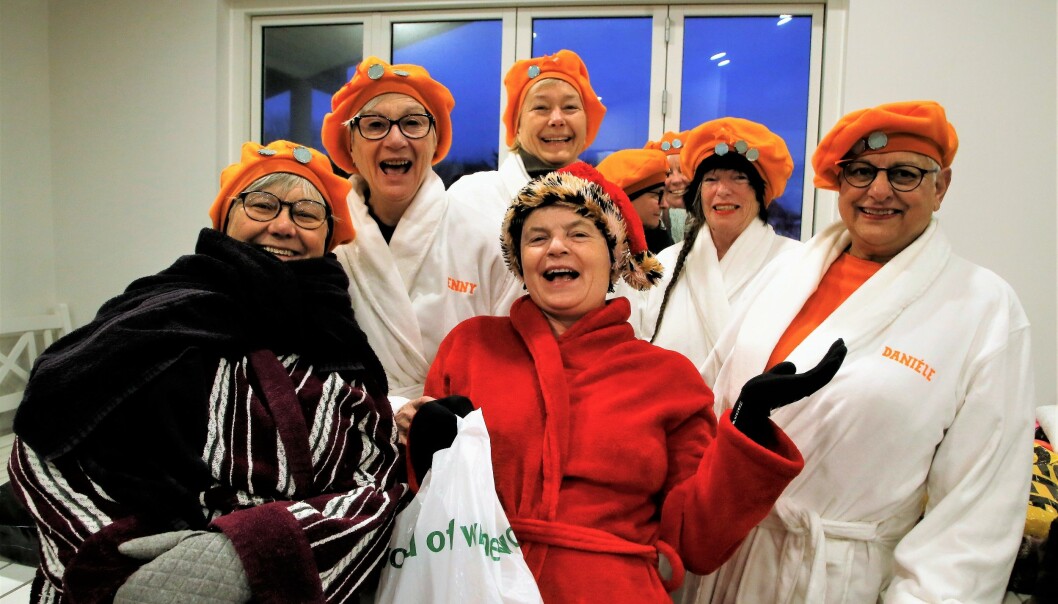 Glada kvinnor i badrock och orangea badmössor.