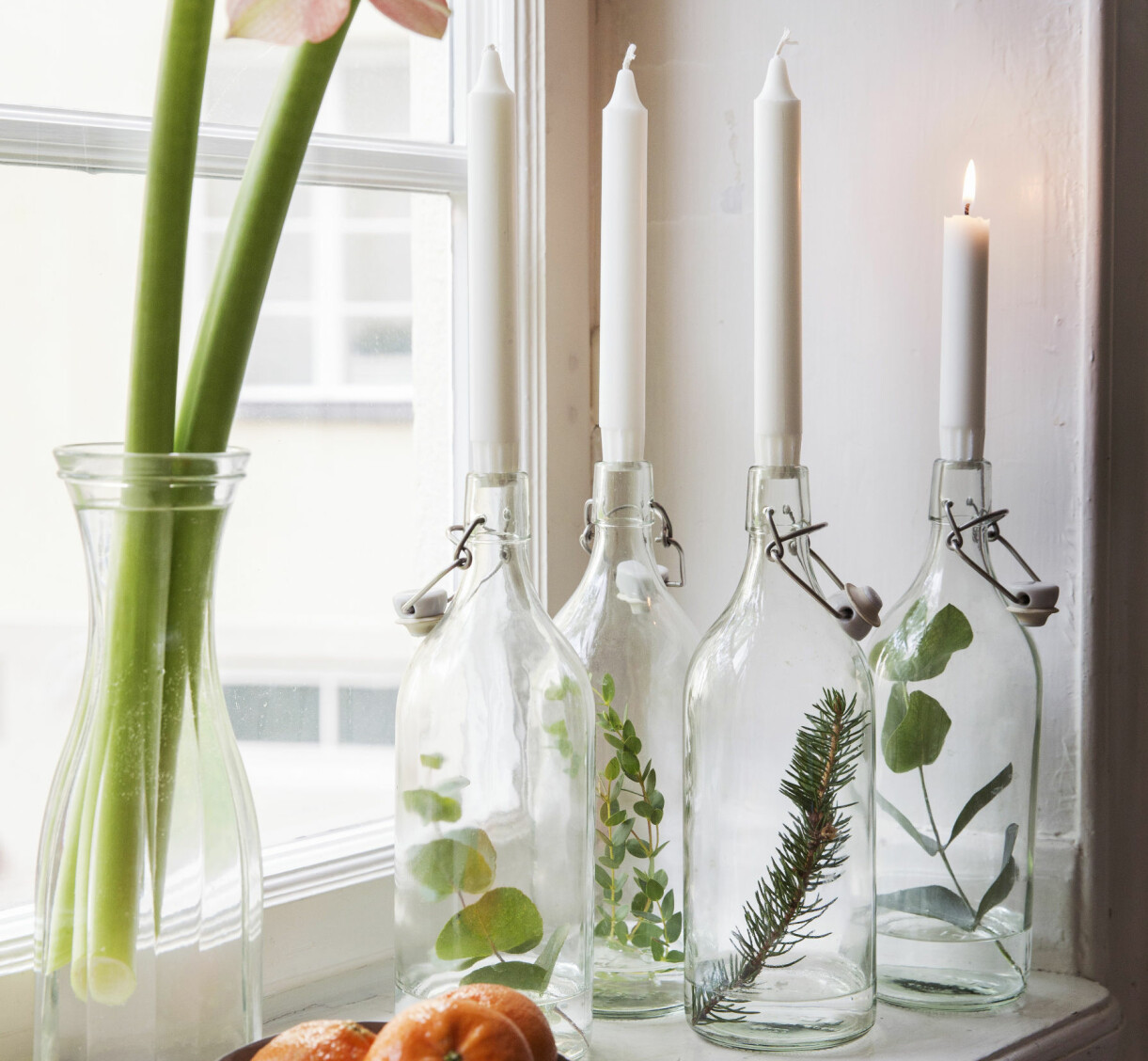 Glasflaskor med kvistar som ljusstakar.