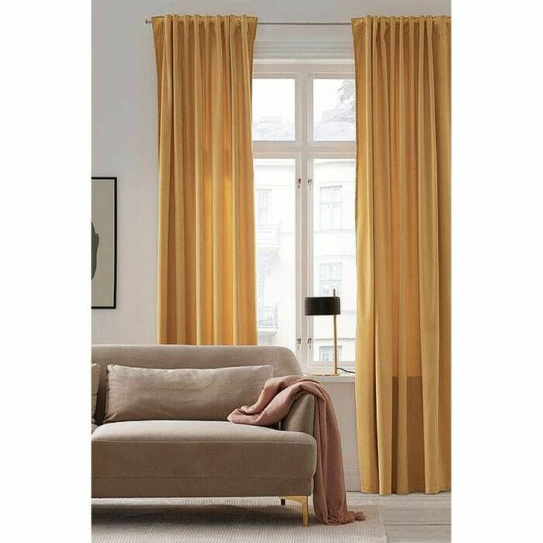 Gula gardiner med mjukt fall från Ellos Home. <a href="http://www.awin1.com/cread.php?awinaffid=439053&awinmid=8905&clickref=gardiner&p=https%3A%2F%2Fwww.ellos.se%2Fellos-home%2Fveckbandslangd-daisy-i-sammet-2-pack-med-kombiband%2F1044015-14" target="_blank" rel="noopener">Här kan du läsa mer och köpa dem</a>. Gula och färgglada gardiner