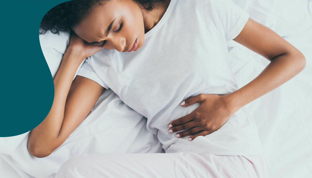 En kvinna ligger i sängen med svåra magsmärtor.