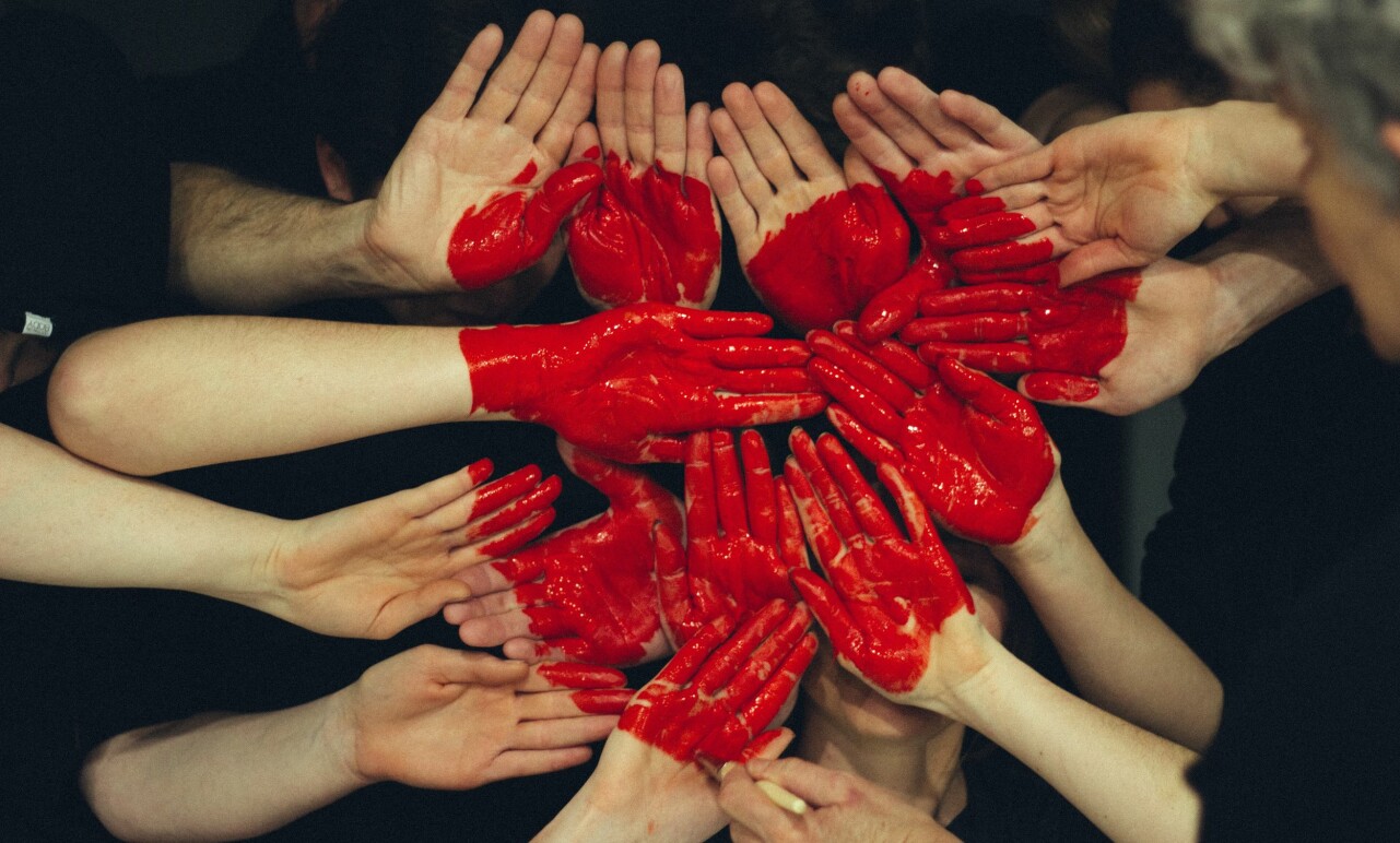 Händer målade med röd färg formar ett hjärta.