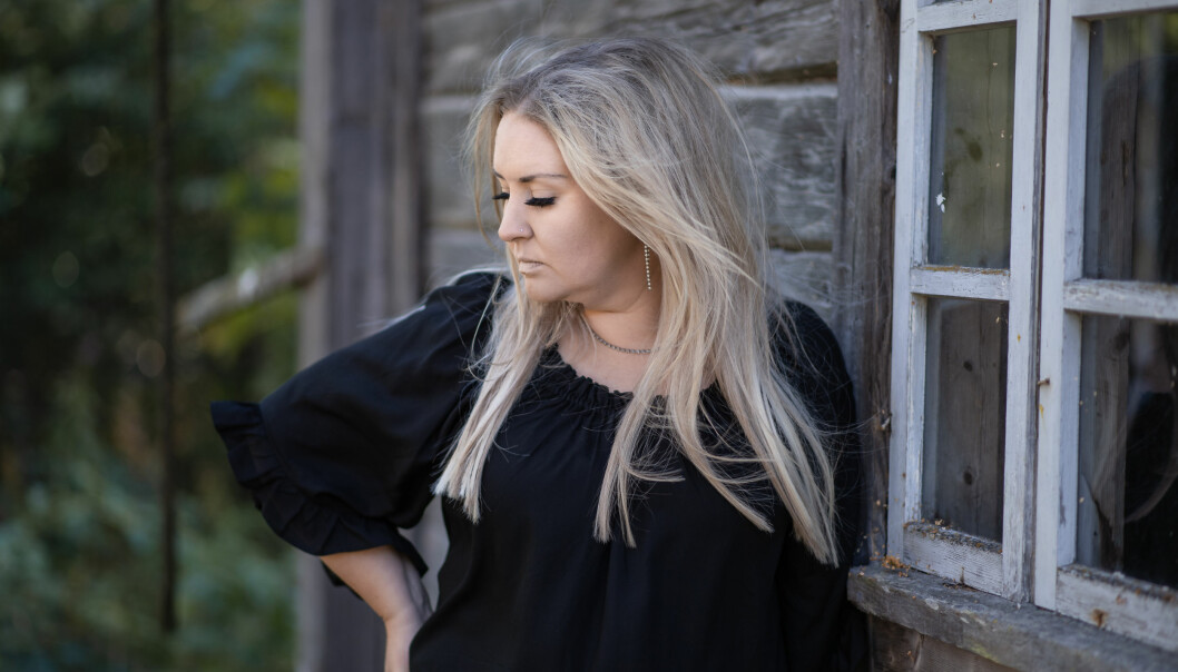 Heidi Mattsson poserar utanför ett timmerstockshus.