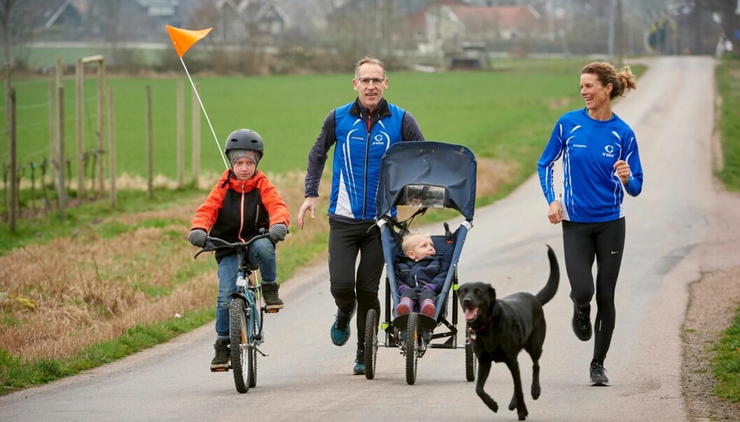Hela familjen är ute och motionerar: Storebror Simon cyklar och lillebror Dennis sitter i vagn medan pappa Sven och mamma Emma springer.