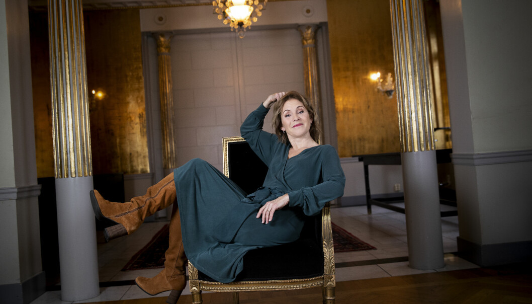Helen Sjöholm sitter i en fåtölj med gulddetaljer inne på Grand hotel i Stockholm.