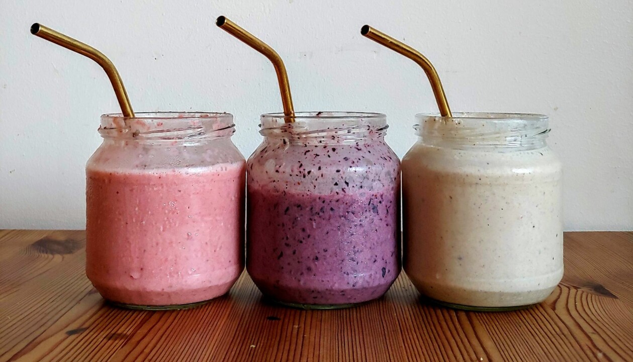 Att leva sparsamt går hand i hand med att leva hållbart. Här har gamla glasburkar diskats och används istället som behållare för smoothies. Tre glasburkar med olika smoothies och tillhörande sugrör av metall.