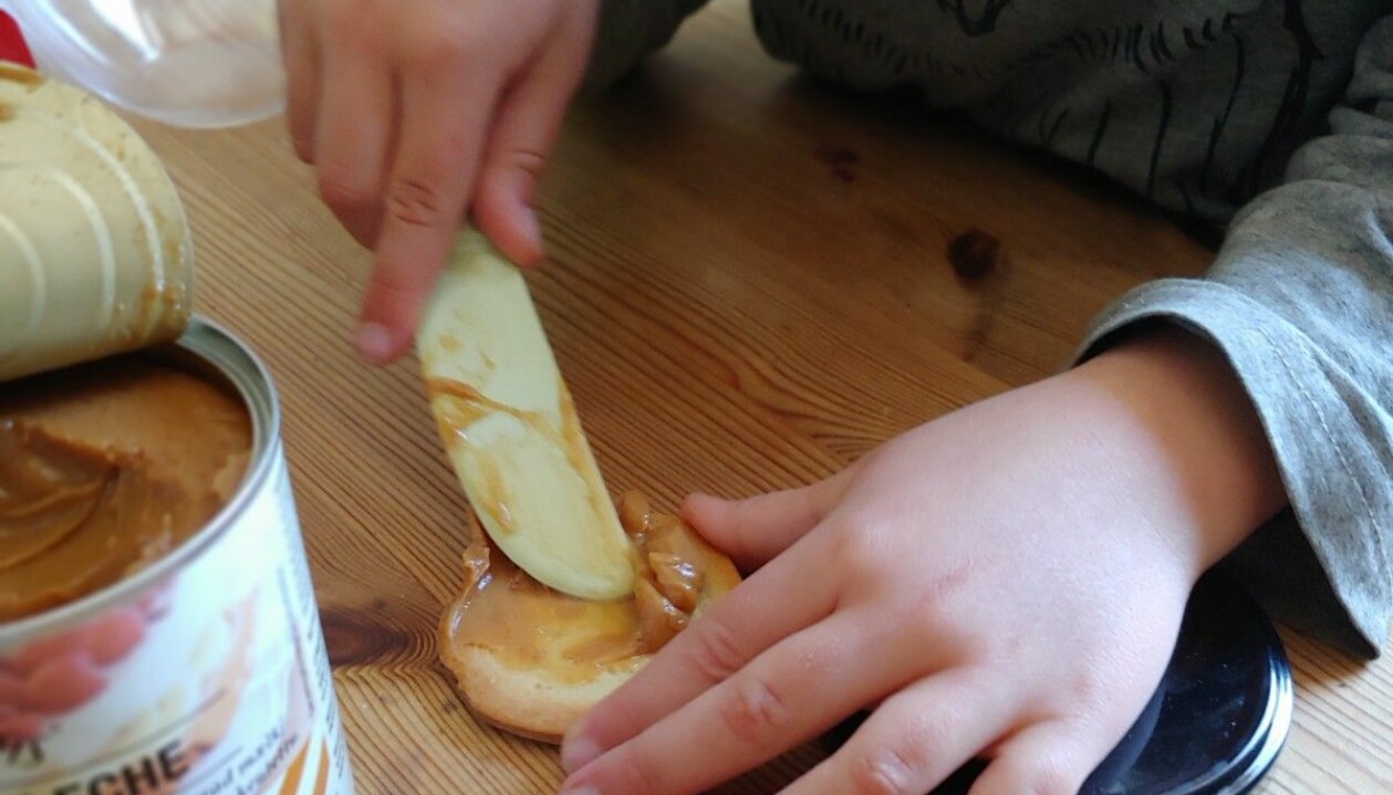 Ett av barnen brer dulce de leche på en kaka.