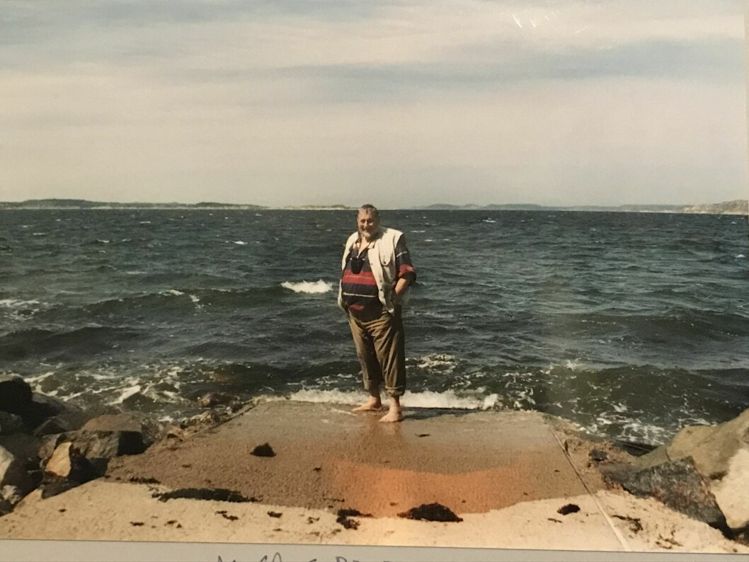 En leende medelåldersman står på en betongperrong vid havet.