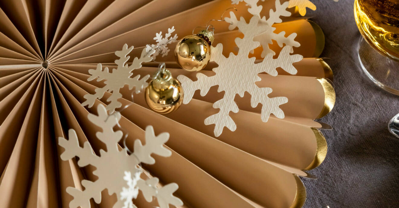 Snöflingor av papper, små julkulor och en papperssnurra i guld