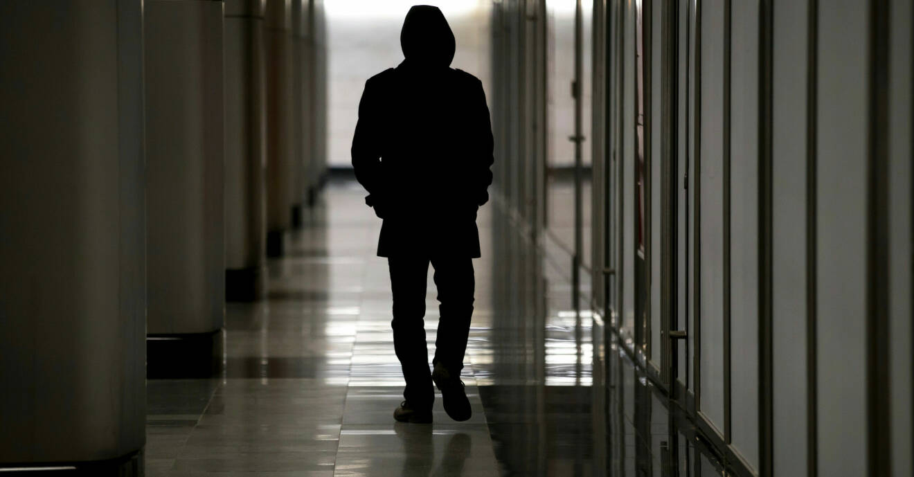 En anonym man går i en korridor.