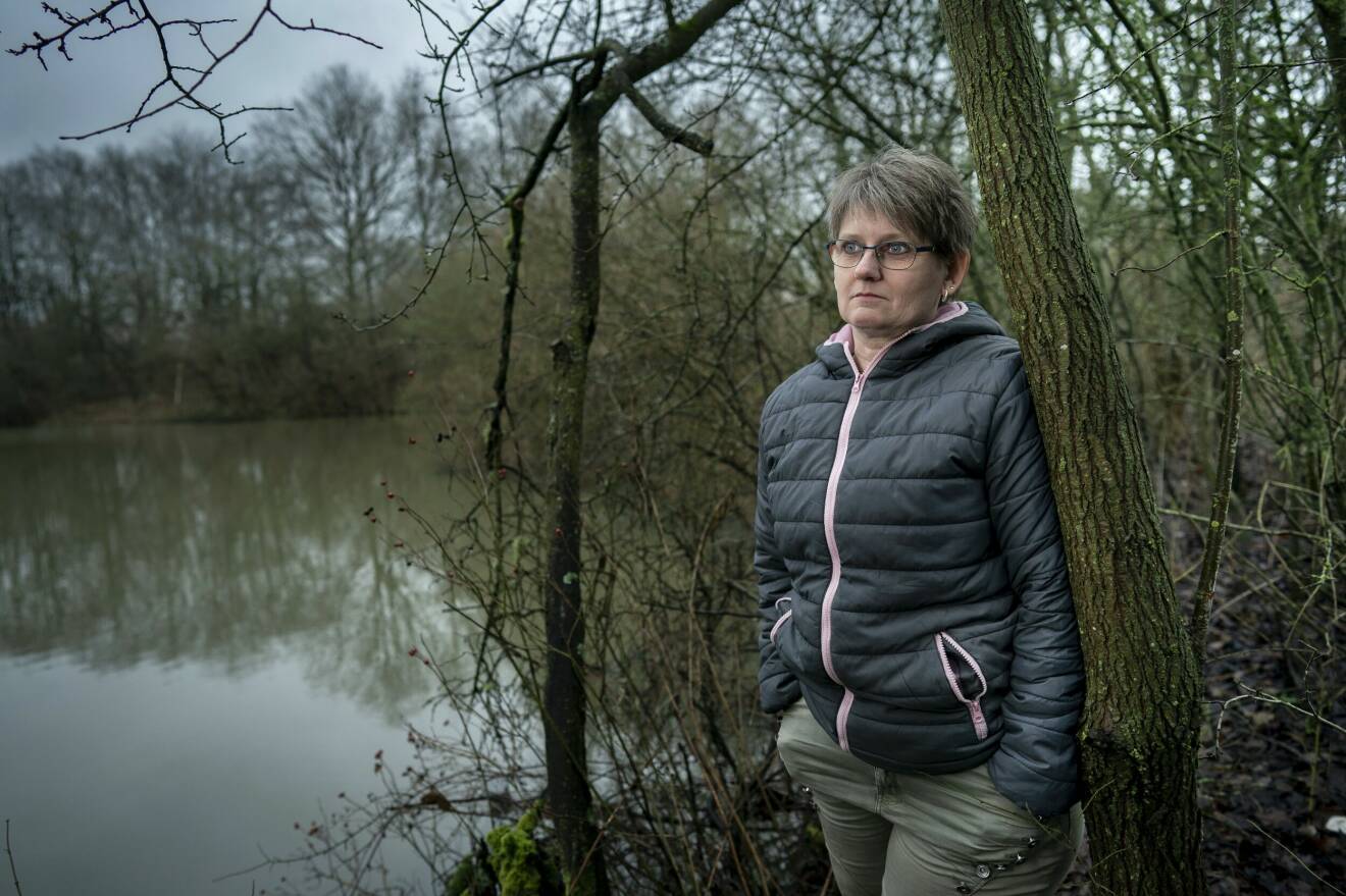 Janni Holmberg Brunn står utomhus i grått väder, intill en sjö.