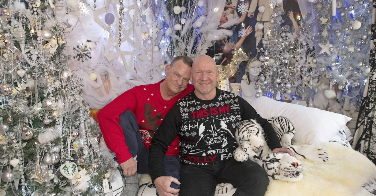 Pehr och Richard i sina jultröjor sitter på sängen. sovrummet som är pyntat i vitt och silver.