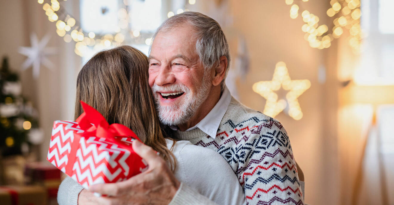 Kvinna ger sin farfar en kram och julklapp.