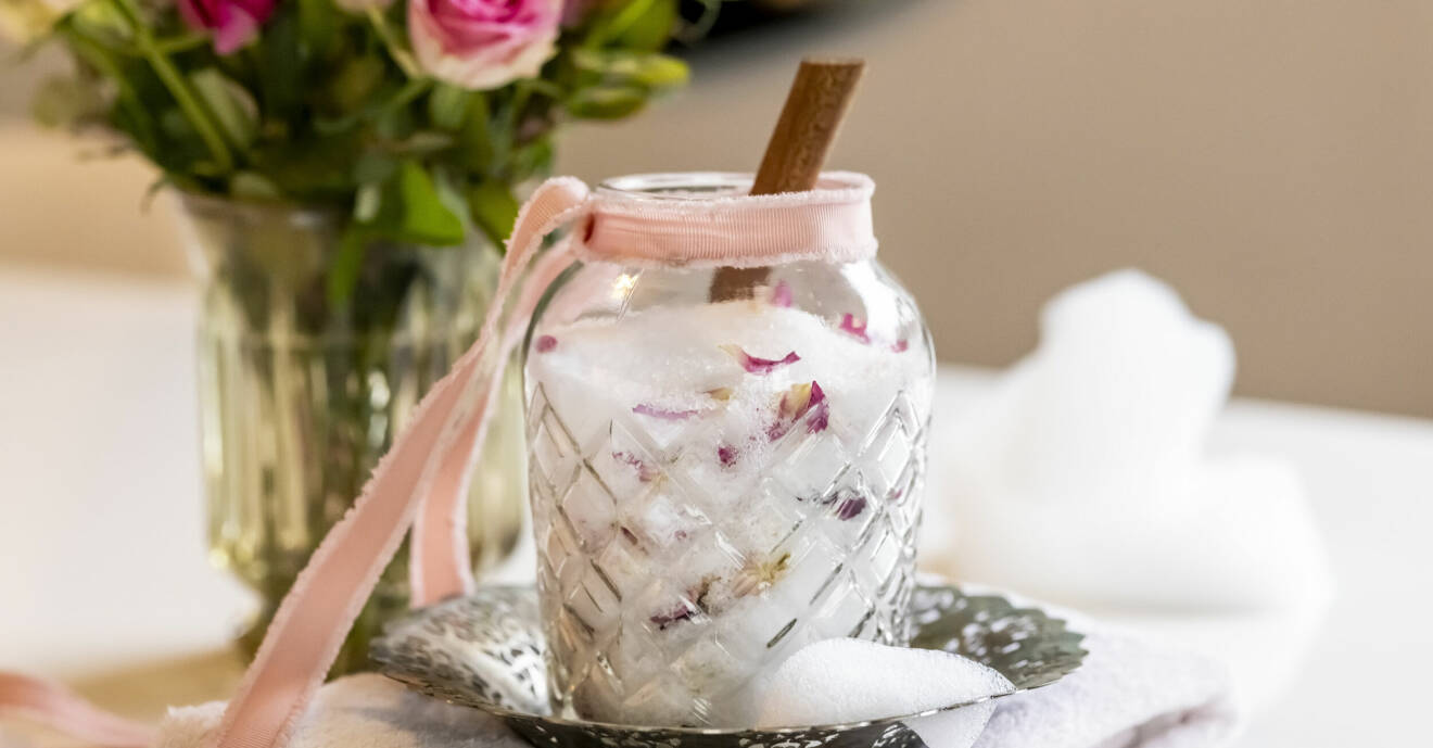 En glasburk med badsalt och rosenblad