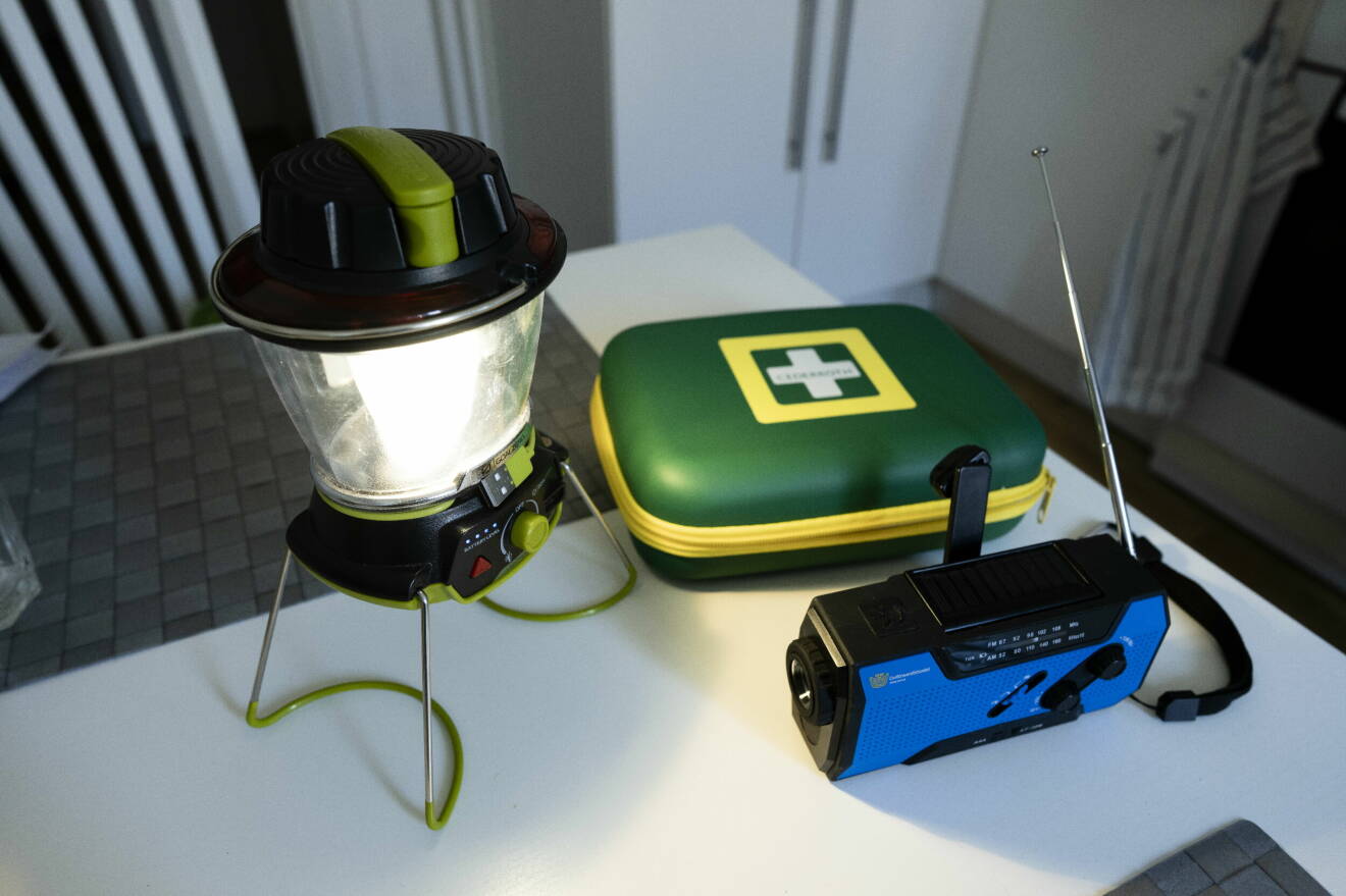 En batteridriven lampa, sjukvårdskit och en vevradio på ett bord hos en prepper.