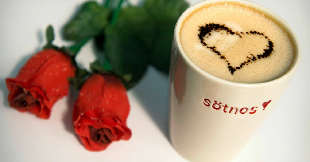 Två röda rosor och en kopp kaffe med ett hjärta i.
