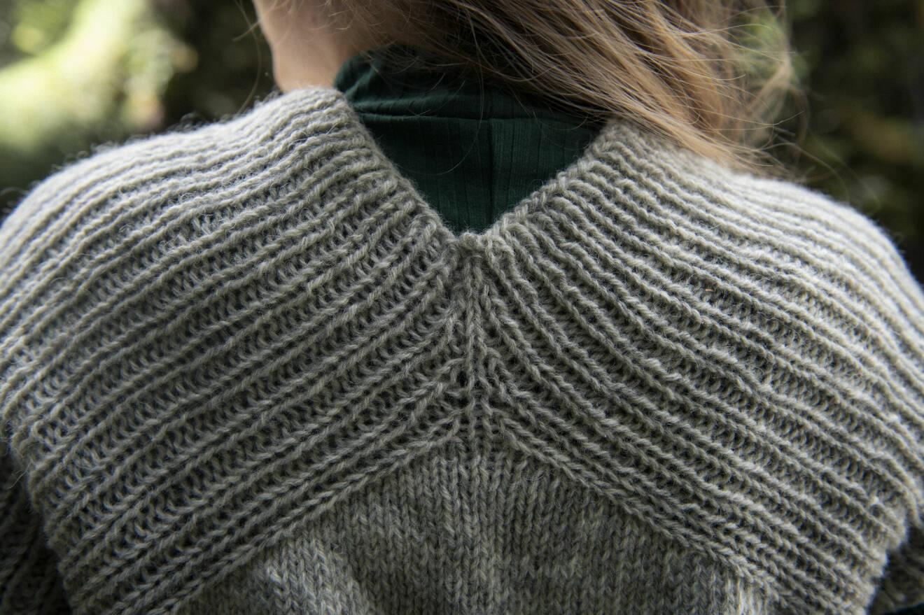 Närbild på baksidan av en grå stickad tröja.