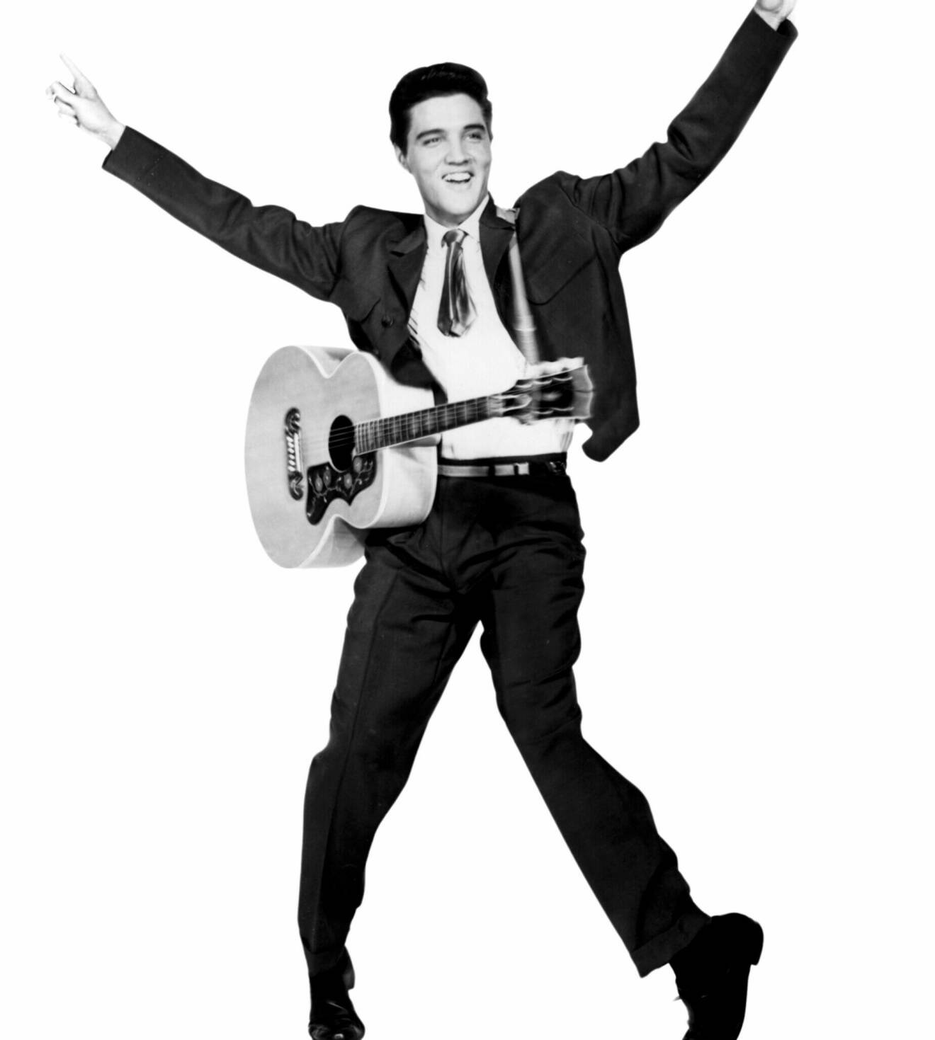 Svartvit bild från 19-50-talet på sångaren Elvis Presley med gitarr på magen.