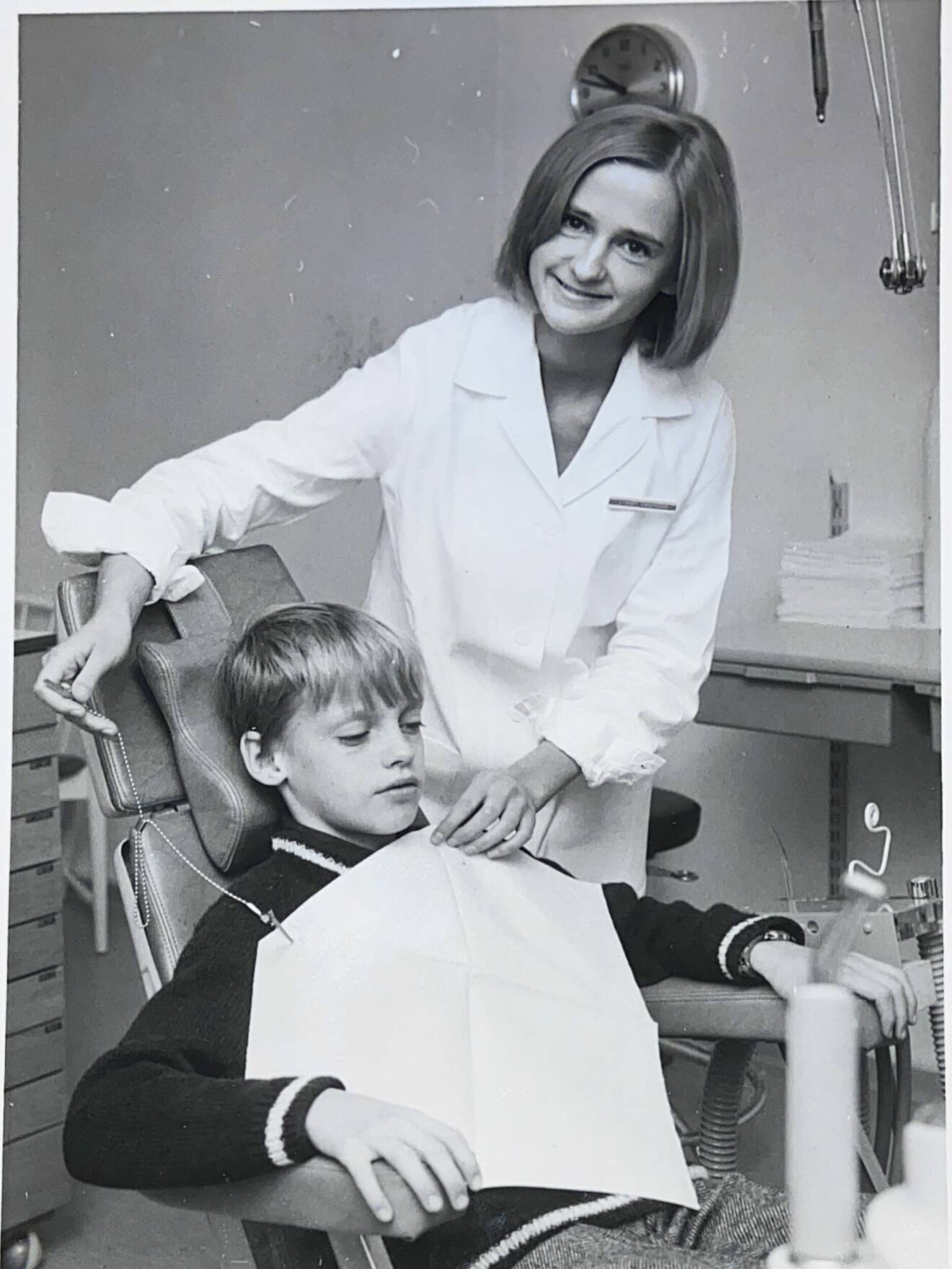 Lisbeth Magnusson, tandsköterska, undersöker en pojke som sitter i en tandläkarstol. Bilden är gammal och svart-vit.