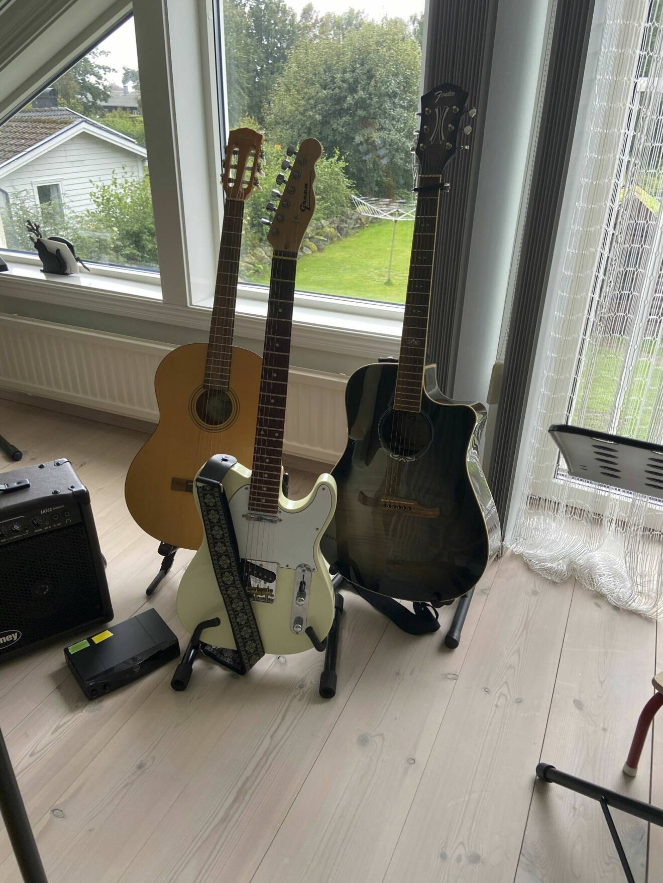 Tre gitarrer på gitarrställ och en högtalare.