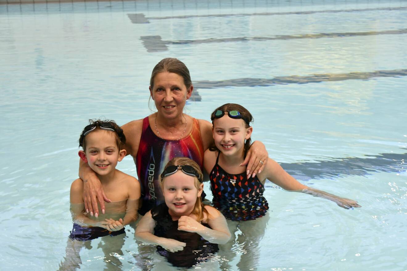 Kicki Eriksson står i en pool tillsammans med tre barn som hon lärt simma.