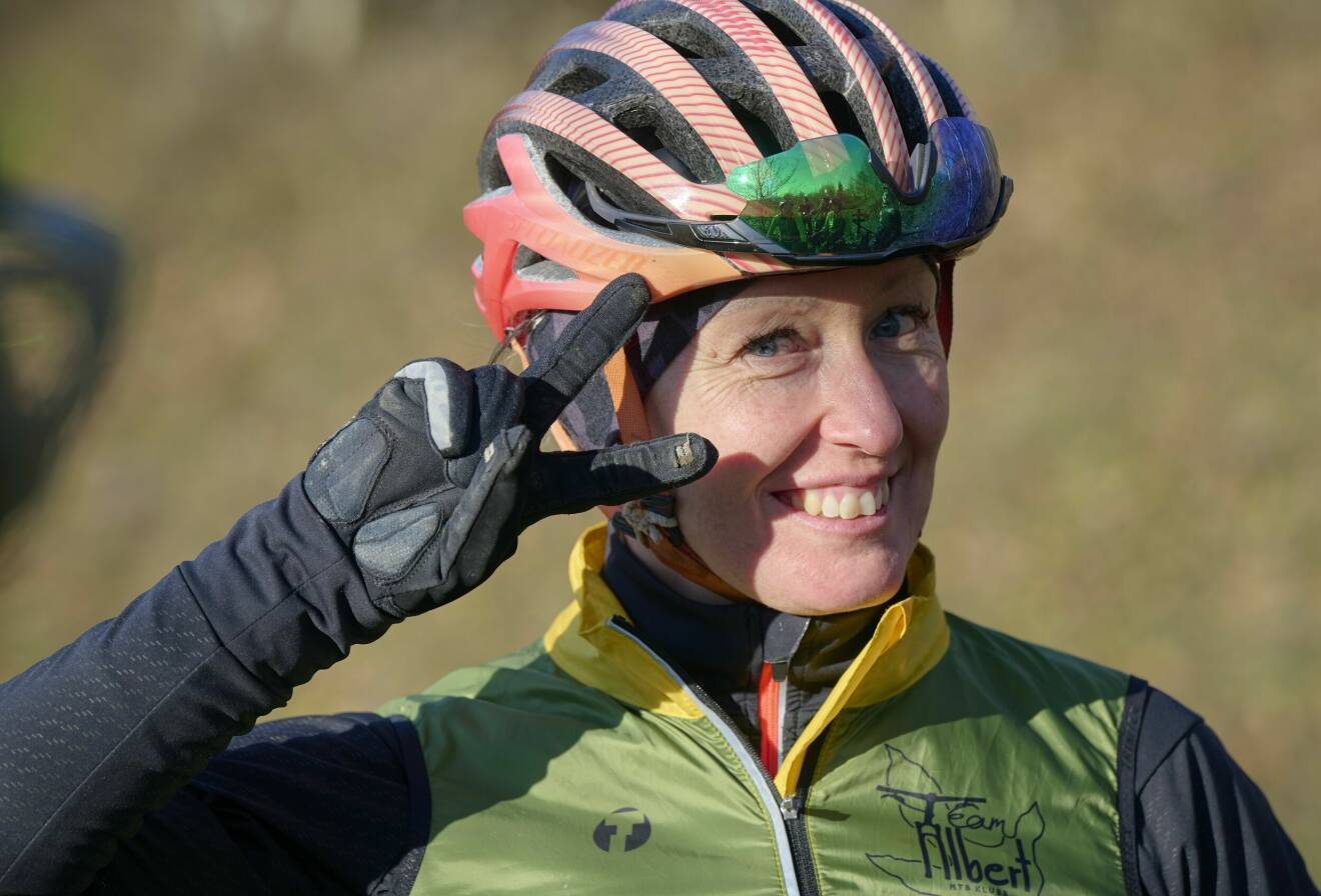 Linda Jansson ler mot kameran och gör fredstecken. Hon bär en cykelhjälm.