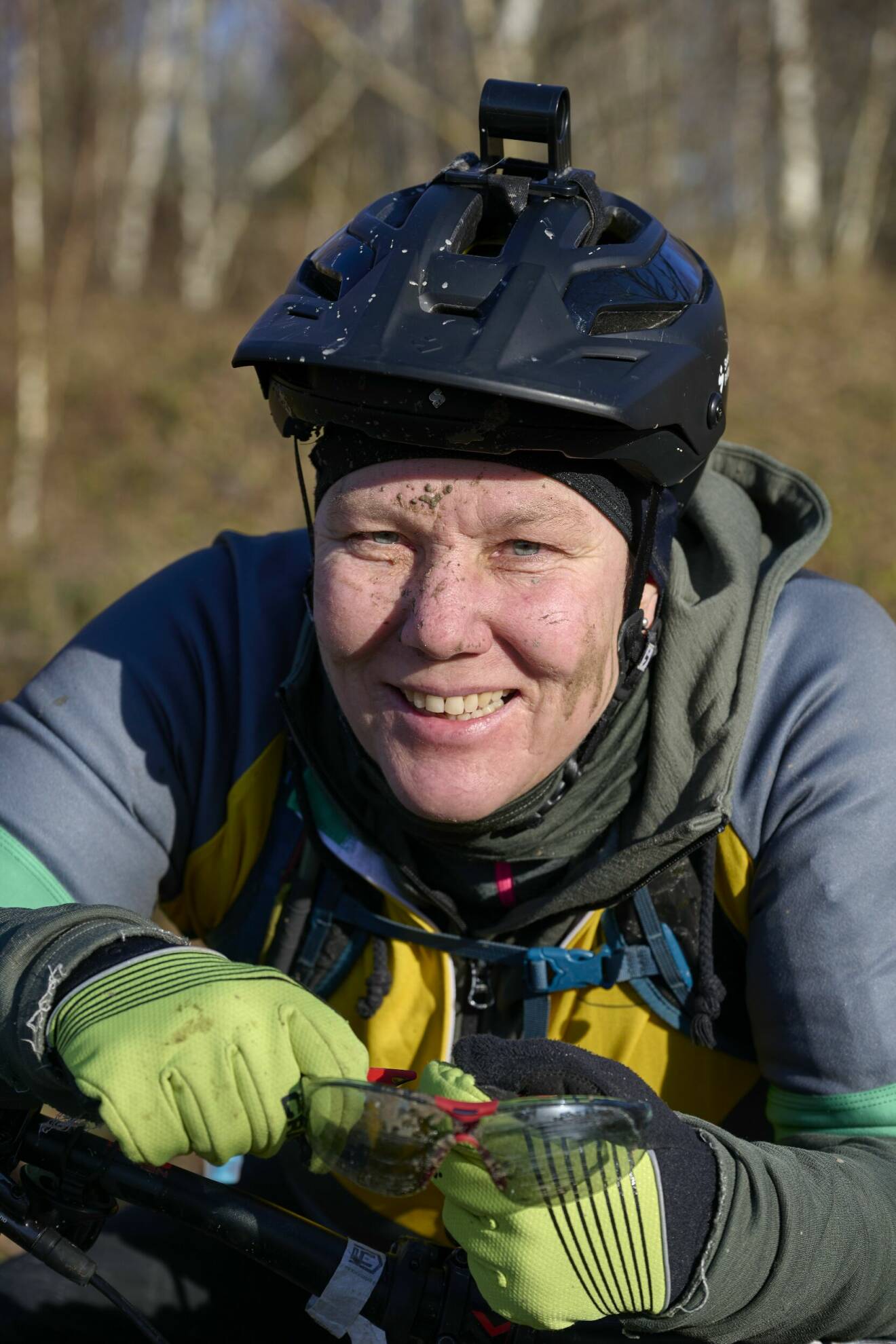 Närbild på Andora Nejsum som ler mot kameran. Hon sitter på en mountainbike och är smutsig i ansiktet.