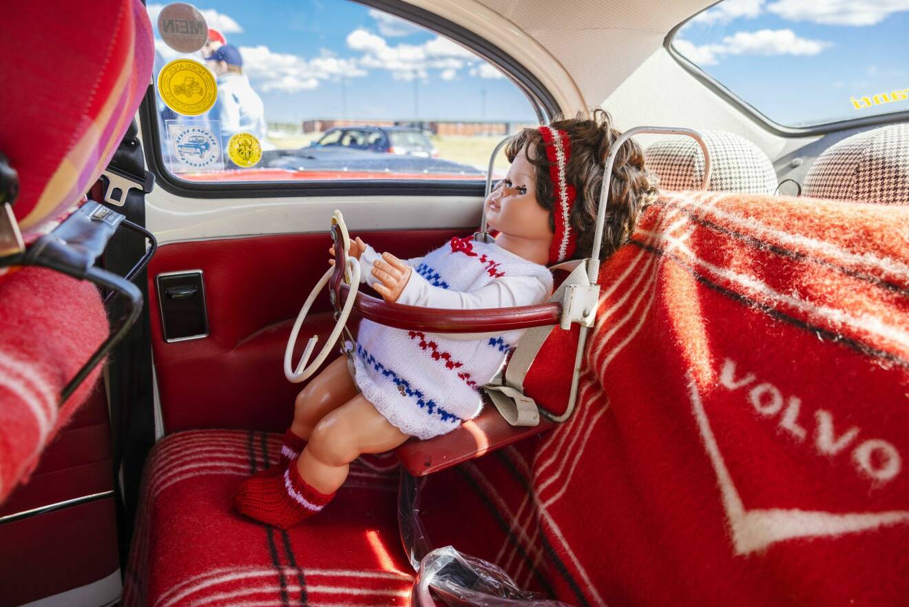 En docka sitter i en vintage bilbarnstol i en Volvo PV från 1963.