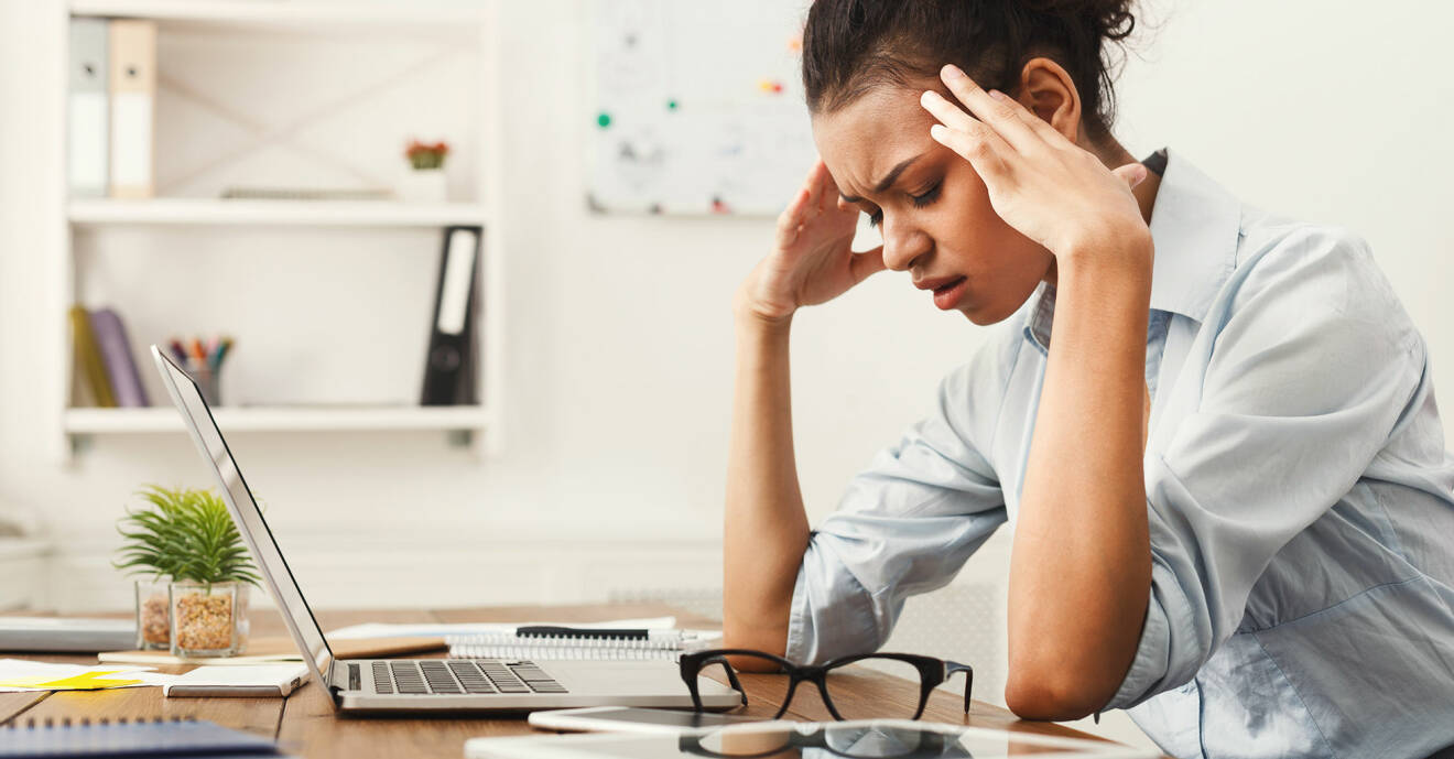 Stressad kvinna hänger över datorn