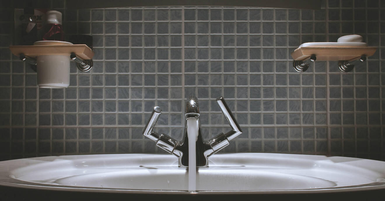En kran i ett badrum spolar vatten som inte rinner undan som det ska.
