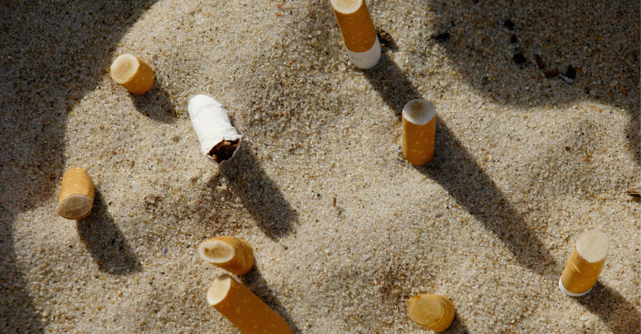 Cigarettfimpar nedtryckta i sand