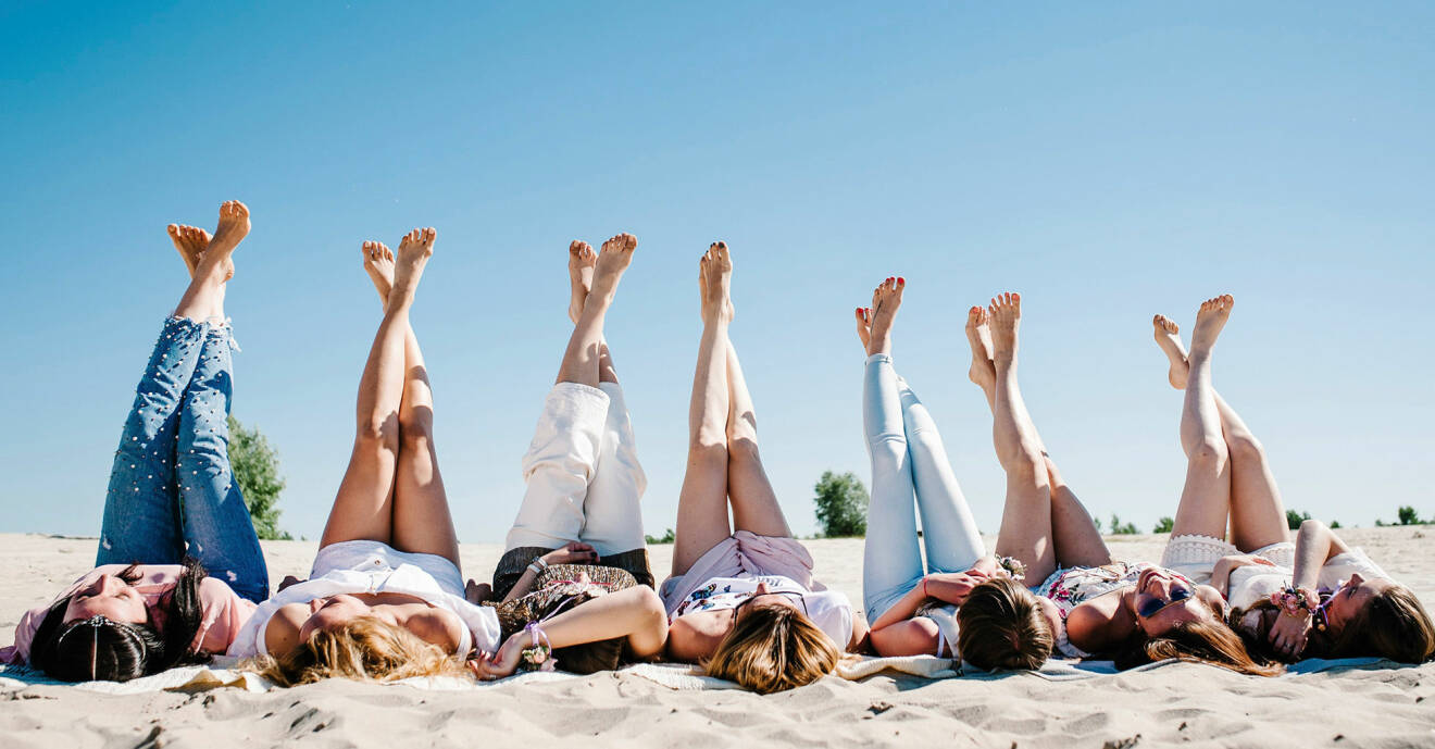 Kvinnor på en strand viftar med fötterna i luften