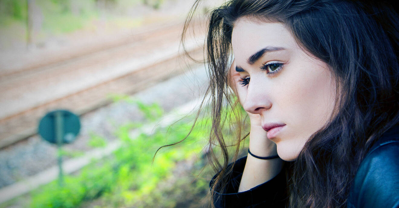 Lena står och tittar ut över ett tågspår.