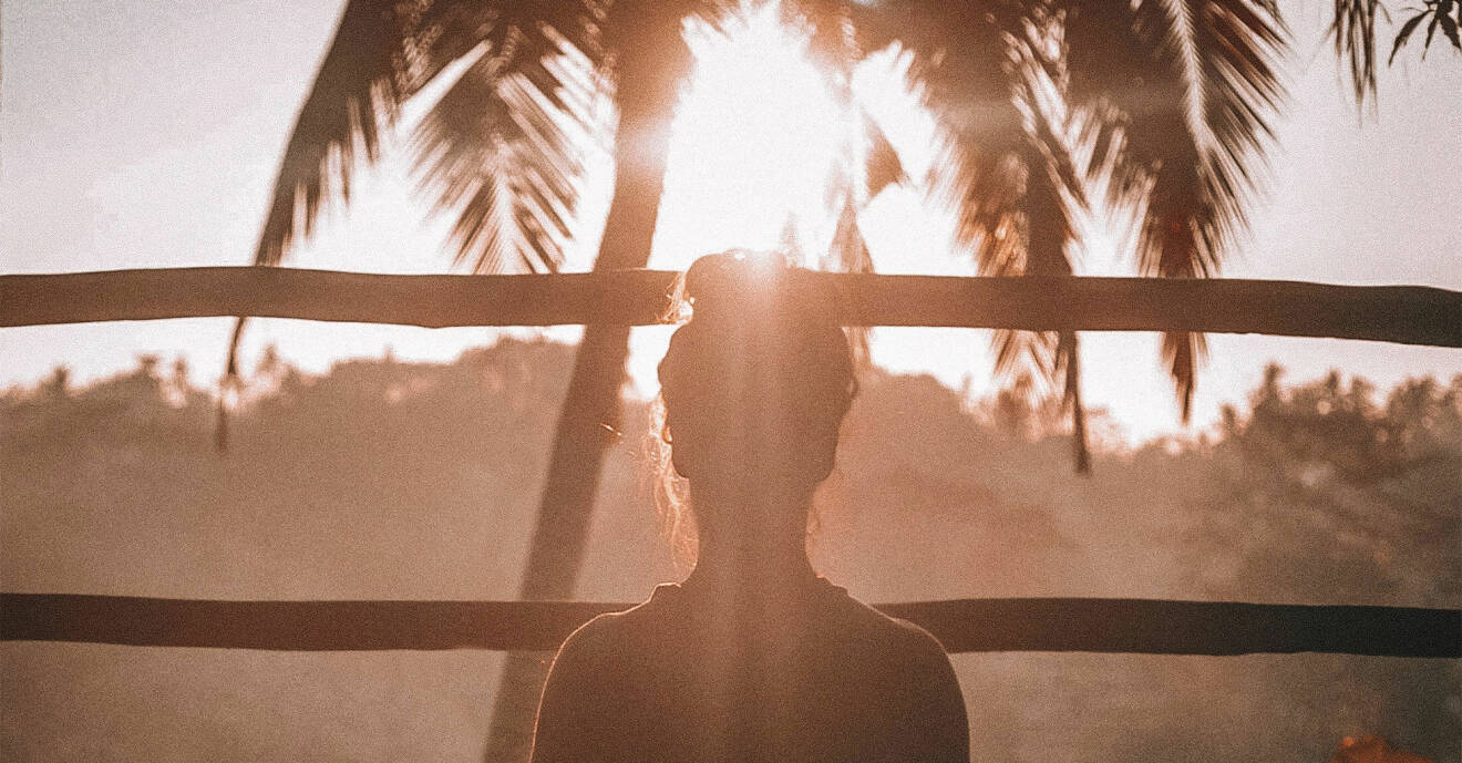 Kvinna njuter av solnedgången och gör yoga.