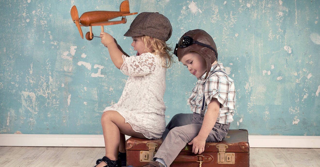 Två barn sitter på en resväska och leker