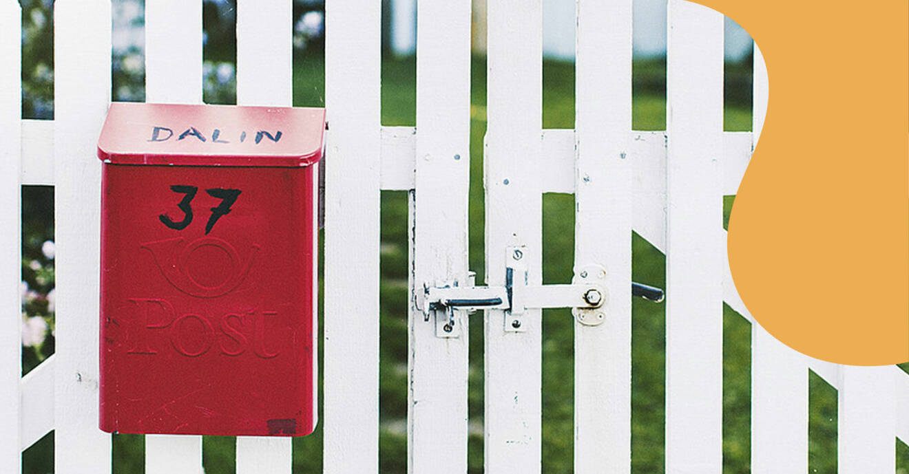 Röd brevlåda sitter på staket.