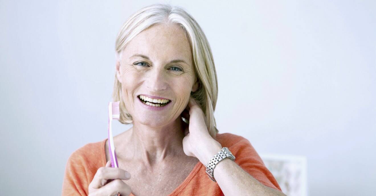 Glad kvinna håller en tandborste i handen