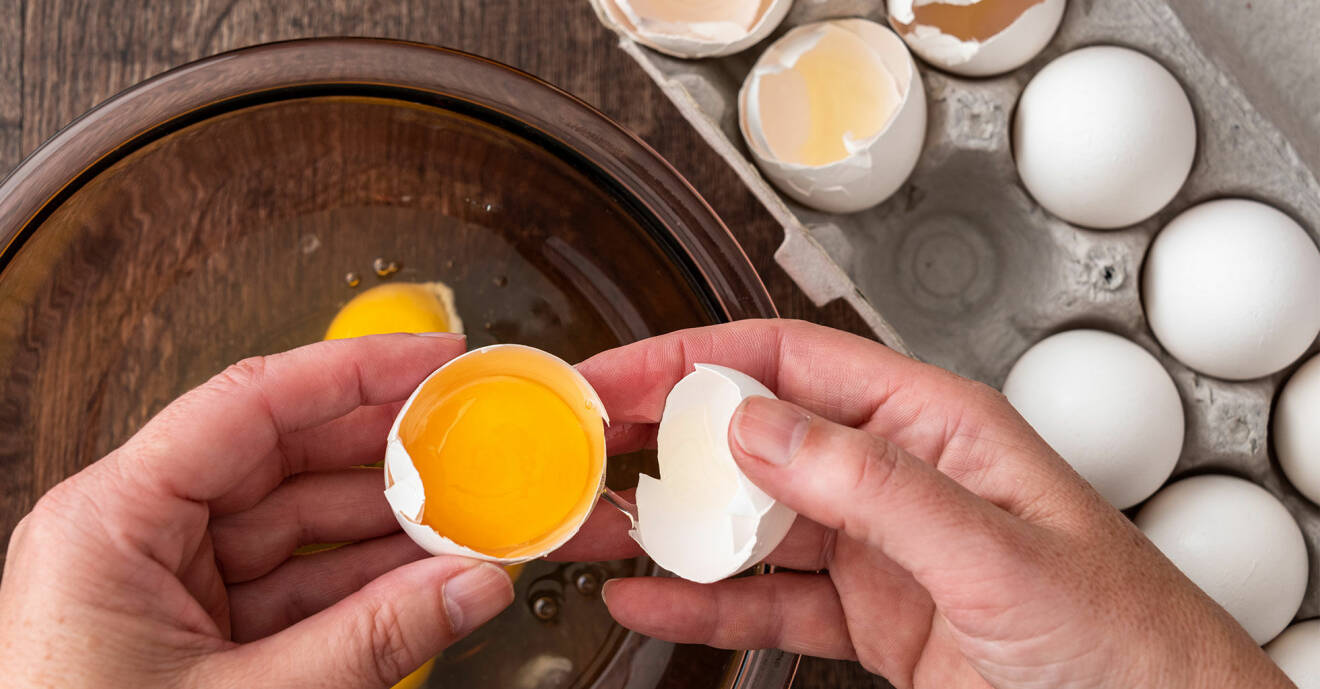 Händer som knäcker ett ägg i en skål.