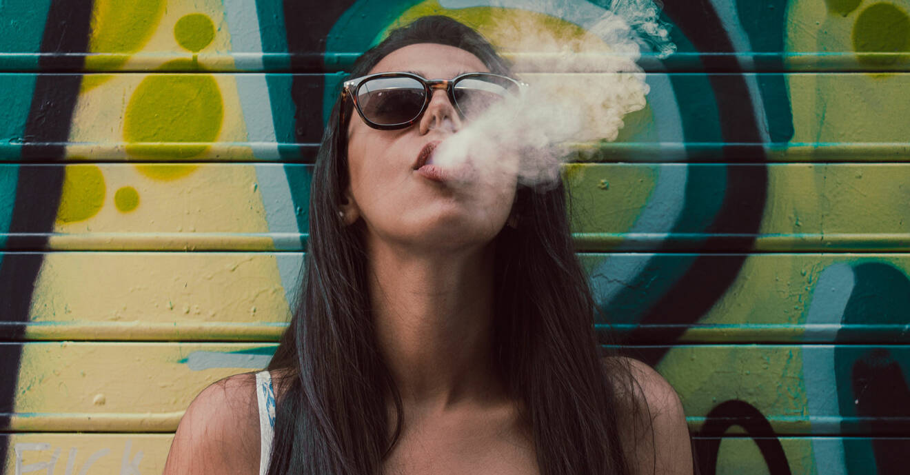 Kvinna blåser ut rök genom munnen