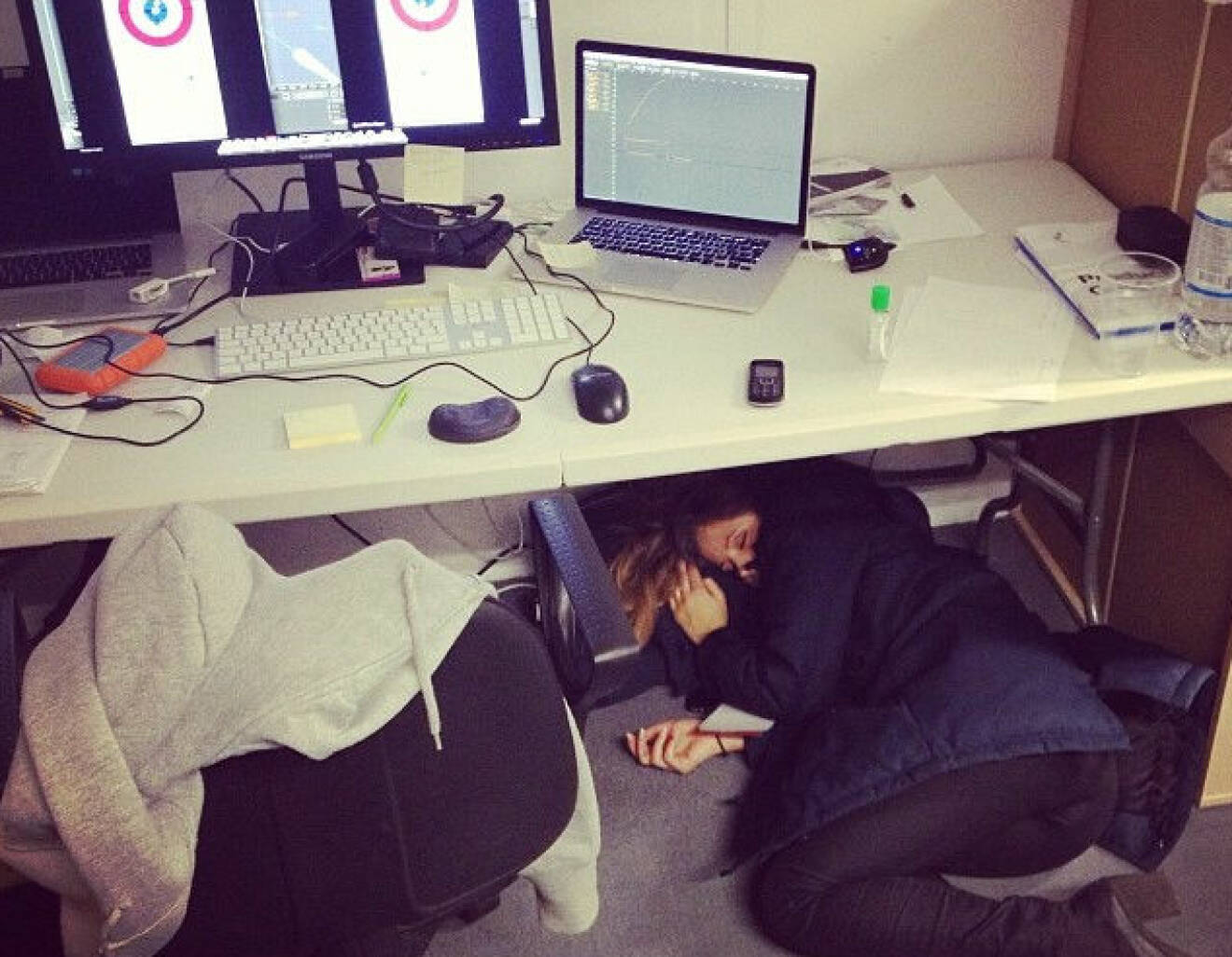 Kvinna ligger och sover under ett skrivbord
