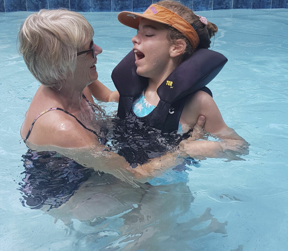 Alicia har ett tecken för att bada – som är det bästa hon vet! Foto: Privat Alicia och mormor Carina badar tillsammans i en pool.